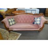 A Victorian mahogany framed and pink upholstered sofa with decorative carved wooden back, 100cm