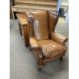 A 20th Century brown leather upholstered wing back armchair, 107cm high