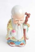 Chinese porcelain figure of a deity decorated in polychrome with a jacket of peaches and holding a