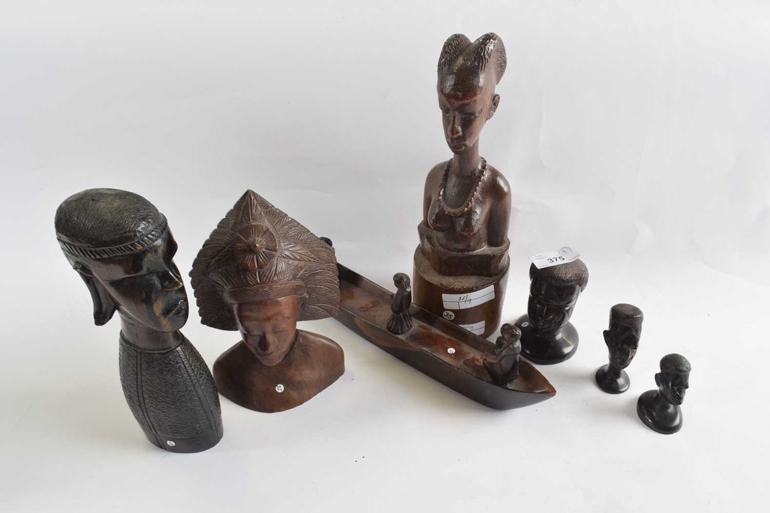 A group of various carved figures and heads and a small carved boat with three figures