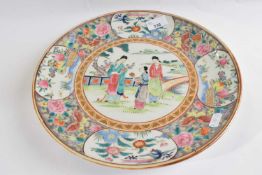 A Chinese porcelain dish with polychrome design of figures in a garden setting, the borders with