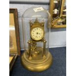 A early 20th Century brass anniversary clock raised on two pillars with glass dome