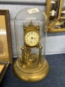 A early 20th Century brass anniversary clock raised on two pillars with glass dome