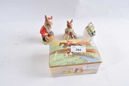 A Crown Devon musical cigarette box with a hunting scene together with two Bunnikins figures and