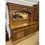 A large 19th Century oak side cabinet formed of two sections with mirrored back over a base with two