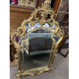 An 18th Century style gilt wood wall mirror with elaborate scrolling and foliate mounted frame,