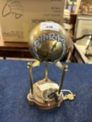 A Art Deco style globe table clock raised on three pillars, the brass globe with white metal