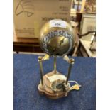 A Art Deco style globe table clock raised on three pillars, the brass globe with white metal