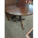 A Georgian mahogany pedestal supper table with circular top raised on a turned column and tripod