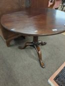 A Georgian mahogany pedestal supper table with circular top raised on a turned column and tripod