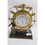 A brass mantel clock shaped as a ships wheel, white enamel dial with black Roman numerals mounted on