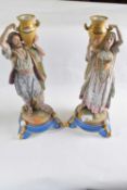 A pair of French bisque porcelain Middle Eastern water carriers on blue circular bases, 40cm high