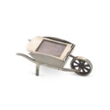 An Edwardian novelty stamp holder in the form of a wheelbarrow, plain polished form bearing