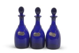 A group of three late 19th/early 20th Century Bristol blue glass decanters with ball stoppers and