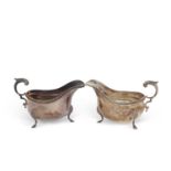 A pair of silver sauce boats of typical form, gadrooned edges, flying capped leaf handles, supported