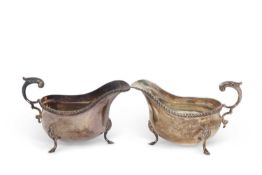 A pair of silver sauce boats of typical form, gadrooned edges, flying capped leaf handles, supported