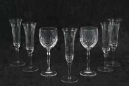 A group of glass ware including five champagne flutes raised on knop and straight stem with engraved