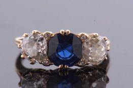 A three stone sapphire and diamond ring, the central off-round cut sapphire, approx. 6.7 x 6.8 x 3.