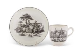A Worcester porcelain cup and saucer with black printed designs of the tea party, base with cross