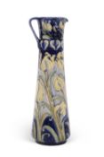 A Florian ware ewer with tube lined design of tulips picked out in yellow on a blue ground within