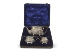 George V silver three piece tea set comprising teapot, cream jug and twin handle sugar bowl of squat