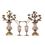 A pair of 19th century Sevres style candelabra the pink ground with gilded panels painted with birds