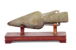 A stone jade type replica of a Chinese harpoon head with carved designs on a wooden display case