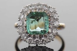 An 18ct emerald and diamond ring, the asscher cut emerald, approx. 8.6 x 8.6 x 4.4mm, surrounded