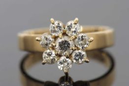 An 18k flowerhead diamond cluster ring, comprised of a central round brilliant cut diamond