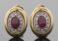 A pair of ruby and diamond earrings, the central collet mounted oval ruby cabochon surrounded by