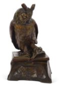 A ceramic model of a "Wise Owl" perched on an open book with a scholar at his studies around the