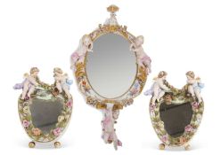 An oval mirror in continental porcelain frame, the frame flanked by two cherubs with cherub below,