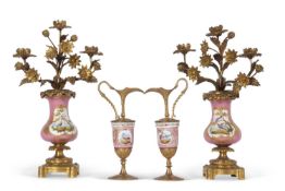 A pair of 19th century Sevres style candelabra the pink ground with gilded panels painted with birds