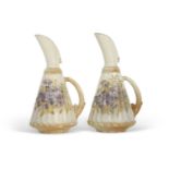 A pair of early 20th Century blush ground Royal Worcester ewers, the ribbed body painted with blue