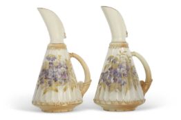 A pair of early 20th Century blush ground Royal Worcester ewers, the ribbed body painted with blue