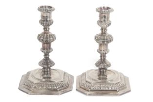 A pair of Elizabeth II silver cast candle sticks in George II style, applied with gadrooned edges
