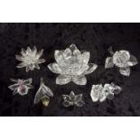 A group of Swarovski crystal flowers including a pink flower, yellow flower, a rose candle holder