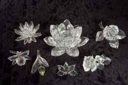 A group of Swarovski crystal flowers including a pink flower, yellow flower, a rose candle holder