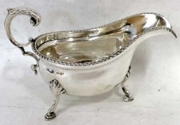 An Edwardian silver sauce boat of typical form with gadrooned rim and a flying scroll handle