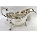 An Edwardian silver sauce boat of typical form with gadrooned rim and a flying scroll handle