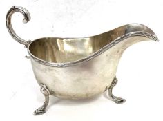 A George V silver sauce boat of typical form, applied reeded rim, flying scroll capped handle,