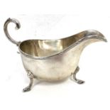 A George V silver sauce boat of typical form, applied reeded rim, flying scroll capped handle,