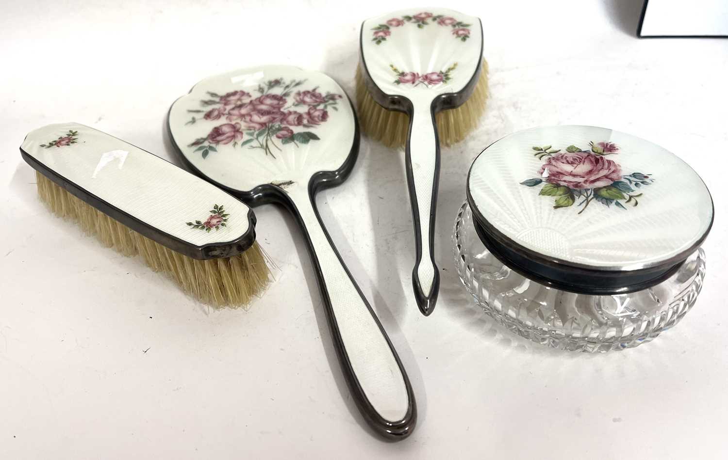 Group of four pieces of enamelled back dressing table wares to include hand mirror, hairbrush and