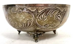 A white metal bowl of squat circular form chased and engraved with foliate panels and supported on