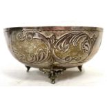 A white metal bowl of squat circular form chased and engraved with foliate panels and supported on