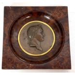 An early 19th Century bronze medallion of Napoleon in portrait relief, framed in a birds eye maple