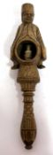 An antique treen box wood nut cracker, a carved figure sitting astride a barrel with screw handle,