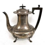 George V silver coffee pot of oval form supported on four hoof feet with ebonised finial and handle,