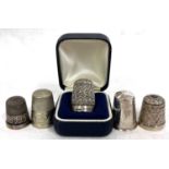 A group of five thimbles to include two hallmarked silver examples, one stamped 925 and two others