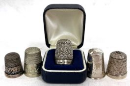 A group of five thimbles to include two hallmarked silver examples, one stamped 925 and two others